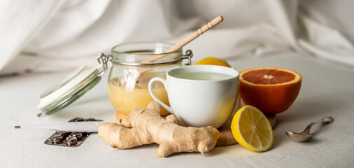 Fototapeta na wymiar Hot tea with ginger, honey, lemon and preparations for cold and a thermometer. Concept of vitamin healthy tea for the sick