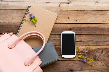 mobile phone ,purse ,notebook and pnk hand bag collection of lifestyle woman relax arrangement flat lay style on background wooden