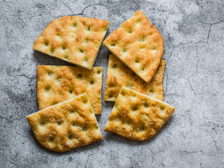 Homemade crunchy italian focaccia on a grey background, top view. Traditional italian bread
