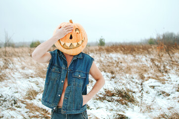 man in a denim jacket over his naked body with a Halloween pumpkin on his head