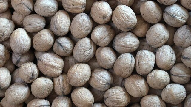 Walnuts in shell close up, top view. Abstract walnuts heap pattern background, rotates. Natural walnut background pattern texture