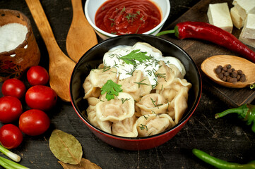 Russian boiled dumplings on a dark table . Traditional dish of Russian cuisine .