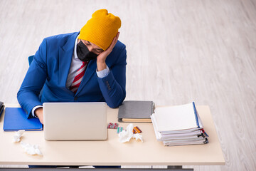 Sick male employee suffering at workplace from coronavirus