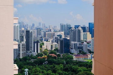 Beautiful Singapore skyline of high rise architecture framed between two buildings, on bright sunny day. Lush greenery in foreground; architectural shot
