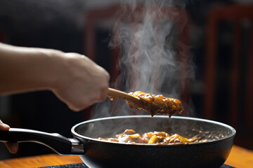 Mussaman Curry with mix vegetables in wok frying pan, Close up of hands of cook frying vegetables on pan, Selective focus at the wooden spoon.