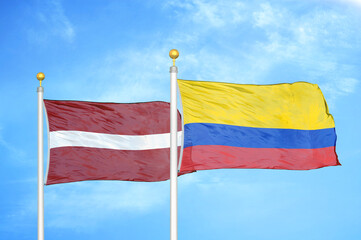 Latvia and Colombia two flags on flagpoles and blue sky