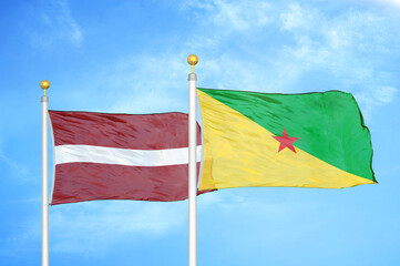 Latvia and French Guiana two flags on flagpoles and blue sky