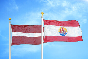 Latvia and French Polynesia two flags on flagpoles and blue sky