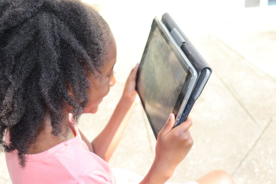 Girl holding tablet electronic device outdoors on summer day close up 