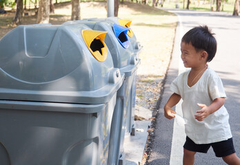 Young boy is going to trow the garbage in the bin.