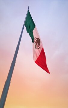 Bandera de M&eacute;xico izada frente a un espectacular atardecer en tonos pastel
