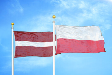 Latvia and Poland two flags on flagpoles and blue sky