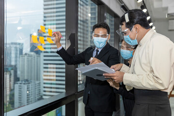 Business in new normal. Office workers wearing face mask and protection while having brainstroming on the wall for new business strategy or plan