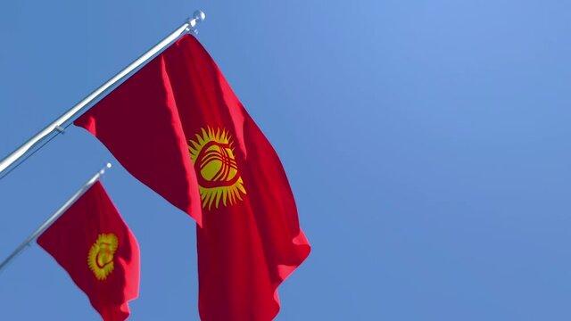 The national flag of Kyrgyzstan is flying in the wind against a blue sky