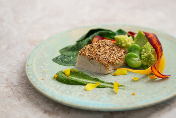 魚料理のモダンで華やかな盛りつけ、彩り豊かな野菜の付け合せ