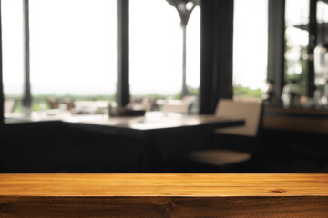 Empty wooden desk space and blurry background of coffee shop or Restaurant for product display montage.