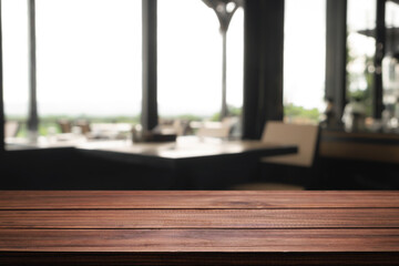 Empty wooden desk space and blurry background of coffee shop or Restaurant for product display montage.
