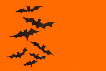 decoration concept for Halloween.  Black paper bats fly upward on an orange background.  template.