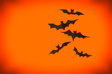 decoration concept for Halloween.  Black paper bats fly in different directions on an orange...