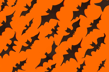 decoration concept for Halloween.  Black paper bats fly in one directions on an orange background.  template