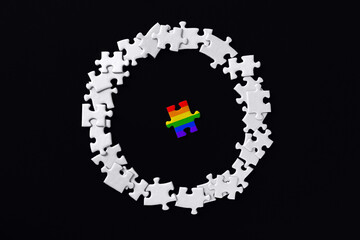 Piece painted in colors of rainbow lies separately. Puzzles are scattered around in circle on background. Concept of equality, acceptance of sexual minorities lesbian, gay, bisexual, transgender.