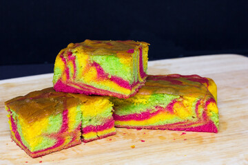 Rainbow marble butter cake with green, yellow and cochineal red food coloring on wooden board