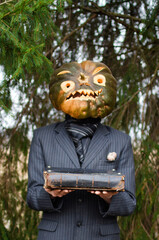 Halloween pumpkin holds an old magic book in its hands