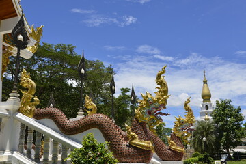 Fototapeta premium Naga Sculpture on staircase with Blue sky and pagoda background, Wat Aran Banphot Sri Chiang Mai District. Nong Khai Province, Thailand.