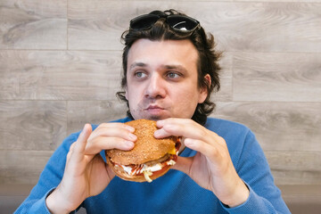 Young man eating a hamburger sitting in a cafe