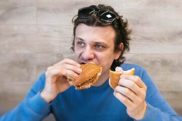 Man eating a hotdog and shawarma simultaneously sitting in cafe