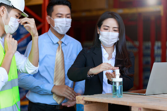Portrait of attractive Asian businessman and investor woman, engineer, wearing protective face mask using alcohol cleansing hands, new normal after Covid-19 Corona virus pandemic.
