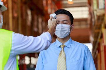 Fototapeta na wymiar Businessman has temperature check at warehouse industry before enter to the workplace, pandemic protective system, new normal employment.