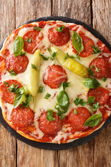 chorizo pizza with hot chili, mozzarella, basil and parsley close-up on a board. vertical top view