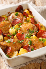 Baked chicken with new potatoes and chorizo close-up in a baking dish on the table. vertical