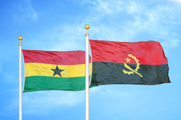Ghana and Angola two flags on flagpoles and blue sky