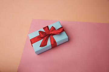 Gift box with red ribbon on a pastel pink background. weightlessness. levitation. Concept of sales, purchases, Christmas holidays and birthdays.
