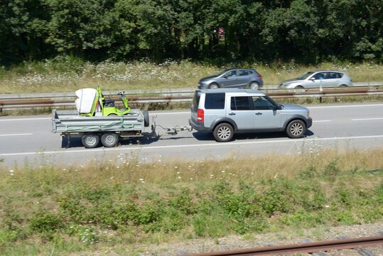 Voiture tractant une remorque avec une tondeuse sur une voie express