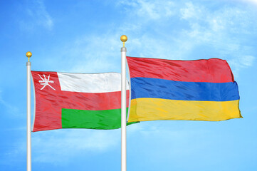 Oman and Armenia two flags on flagpoles and blue sky