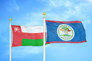 Oman and Belize two flags on flagpoles and blue sky