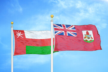 Oman and Bermuda two flags on flagpoles and blue sky
