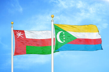 Oman and Comoros two flags on flagpoles and blue sky