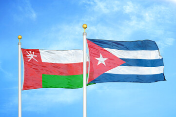 Oman and Cuba two flags on flagpoles and blue sky