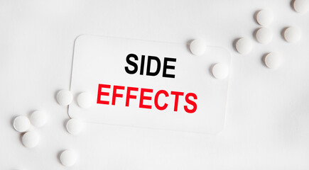 On a white vise sign SIDE EFFECTS, next to white tablets. The second word is highlighted in red.