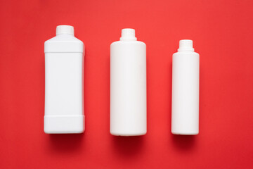 Three detergent bottles on red flat lay background.