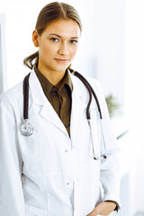 Woman-doctor standing and looking at camera. Perfect medical service in clinic