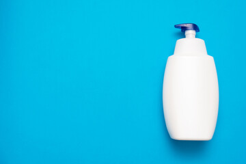 White liquid soap bottle on the blue flat lay background with copy space.