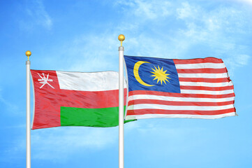 Oman and Malaysia two flags on flagpoles and blue sky
