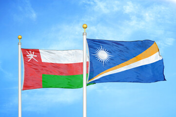 Oman and Marshall Islands two flags on flagpoles and blue sky