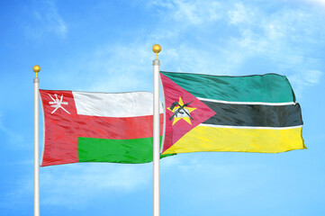 Oman and Mozambique two flags on flagpoles and blue sky