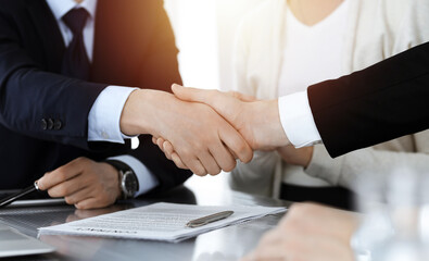 Business people shaking hands after contract signing in sunny modern office. Teamwork and handshake concept